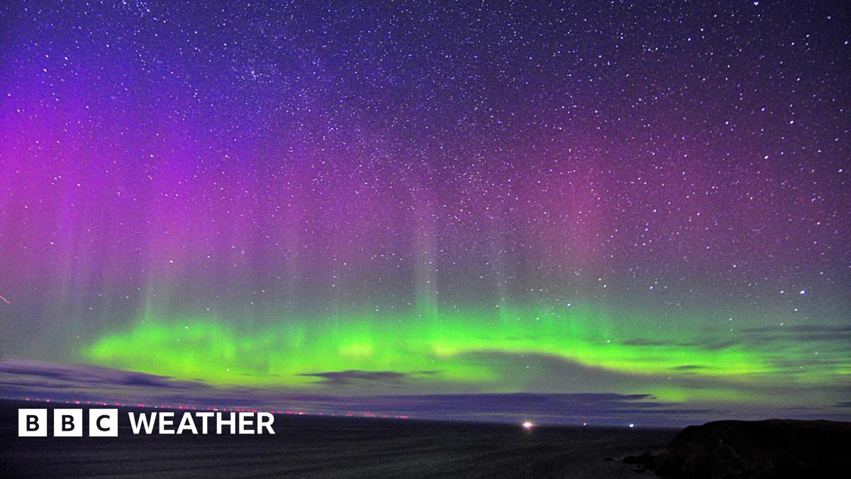 The northern lights shining bright in the night sky with bright green colours in the lower part of the sky and purples higher up