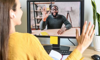 businesswoman waves at a colleague she's meeting with in a Zoom call