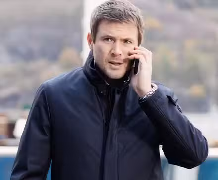 John Reardon on the phone looking tense in Hudson & Rex