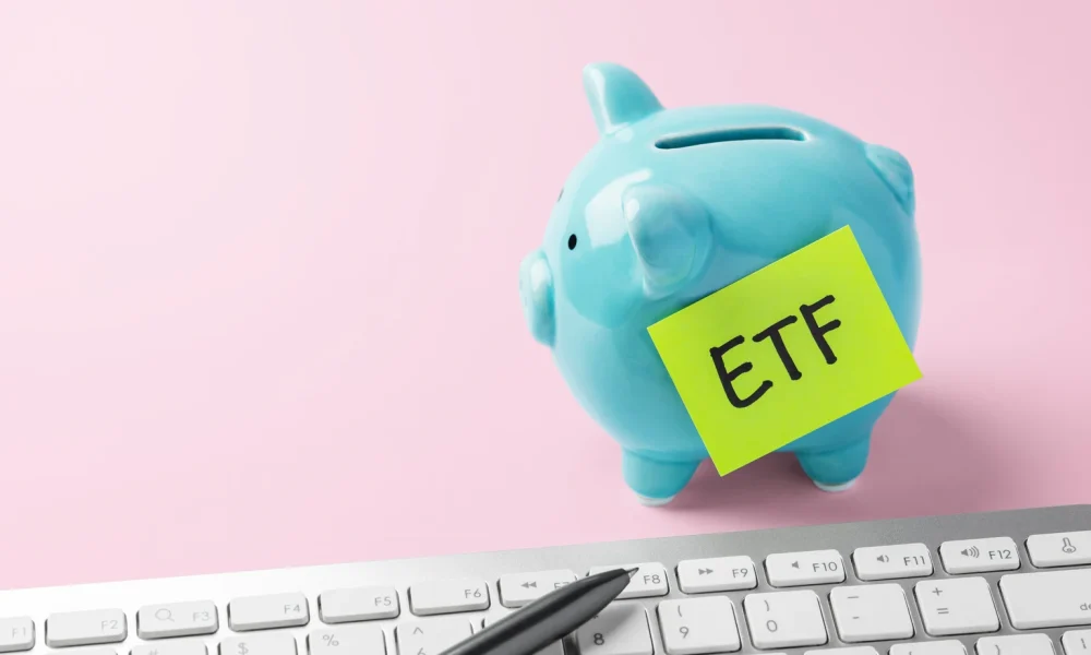 Financial planning and savings for ETF investment. Piggy bank and computer keyboard on pink background