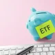 Financial planning and savings for ETF investment. Piggy bank and computer keyboard on pink background