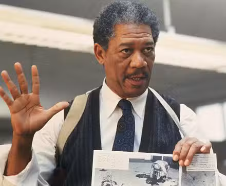 Actor Morgan Freeman as Somerset, holding up a piece of evidence and his hand in Se7en