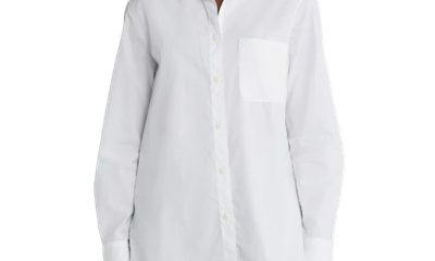 A woman wearing a white button-front blouse untucked, with blue jeans