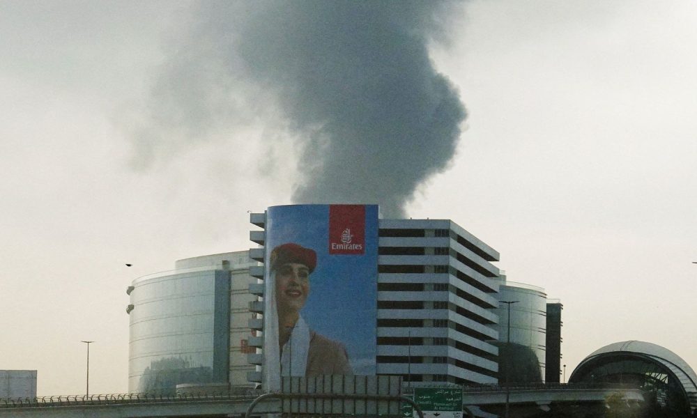 Smoke rising from a burning fuel tank near Dubai International Airport, seen through the windshield of a vehicle. Pic: Reuters