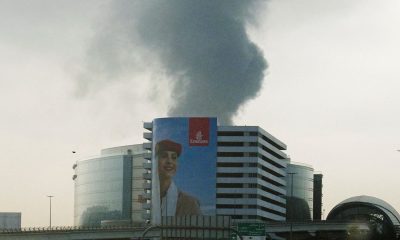 Smoke rising from a burning fuel tank near Dubai International Airport, seen through the windshield of a vehicle. Pic: Reuters