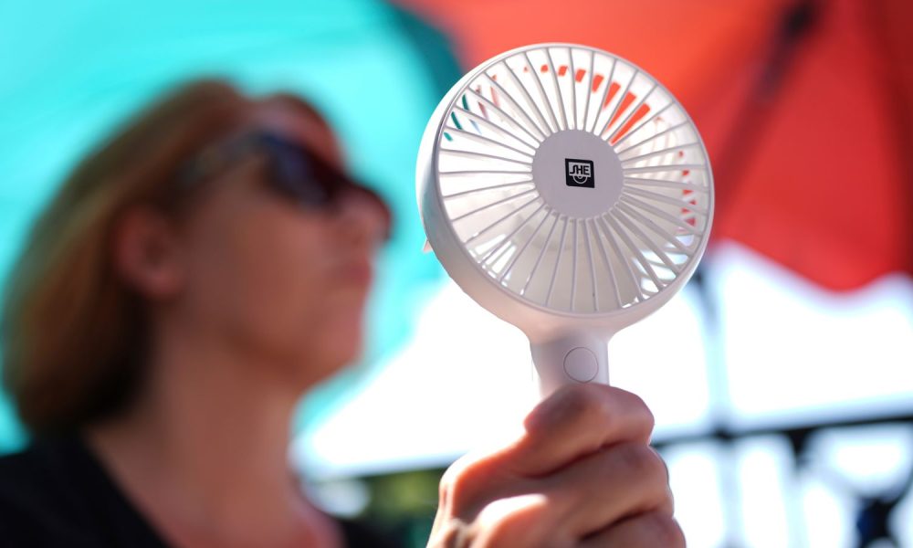 A woman cools herself with a hand fan in Hamburg during a heatwave in Germany in July 2025. Pic: AP