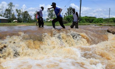 People cross a flooded portion of the road following heavy rains in Nyakach, western Kenya. Pic: AP