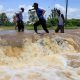 People cross a flooded portion of the road following heavy rains in Nyakach, western Kenya. Pic: AP