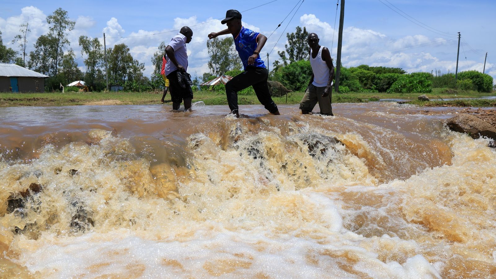 People cross a flooded portion of the road following heavy rains in Nyakach, western Kenya. Pic: AP
