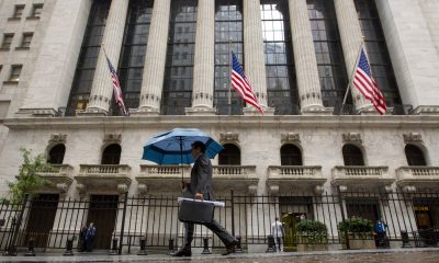 The tech sector led record gains in the S&P 500 index. Pictured: a man with umbrella walks past the New York Stock Exchange.