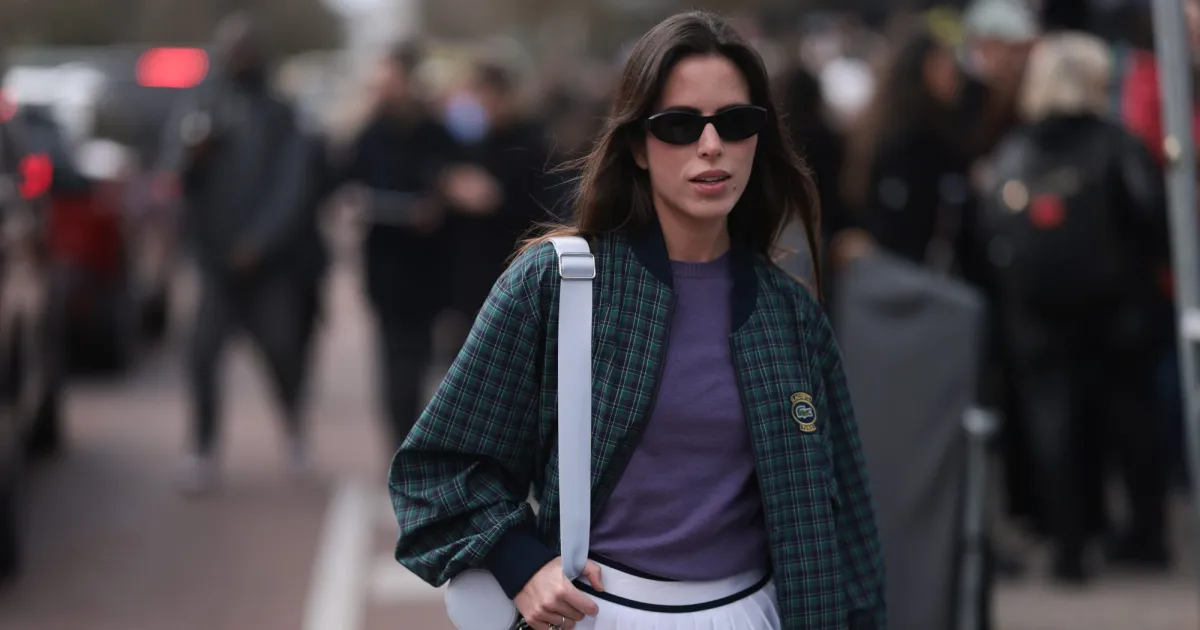 PARIS, FRANCE - MARCH 05: Nina Urgell Cloquell seen wearing a white tennis skirt, green and black checkered Lacoste jacket, purple shirt, black shades, black leather loafer, pink socks and a white Lacoste bag outside Lacoste Show during the Womenswear Fall/Winter 2024/2025 as part of Paris Fashion Week on March 05, 2024 in Paris, France. (Photo by Jeremy Moeller/Getty Images)