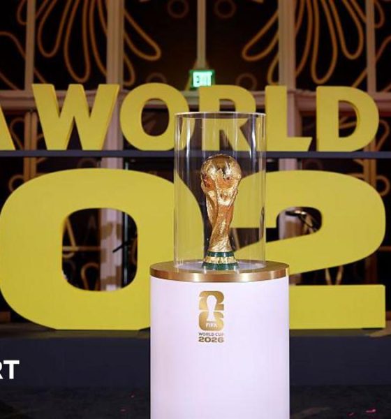 The World Cup on display on a white stand prior to the draw in December in Washington with Fifa World Cup 2026 in big gold letters in the background.