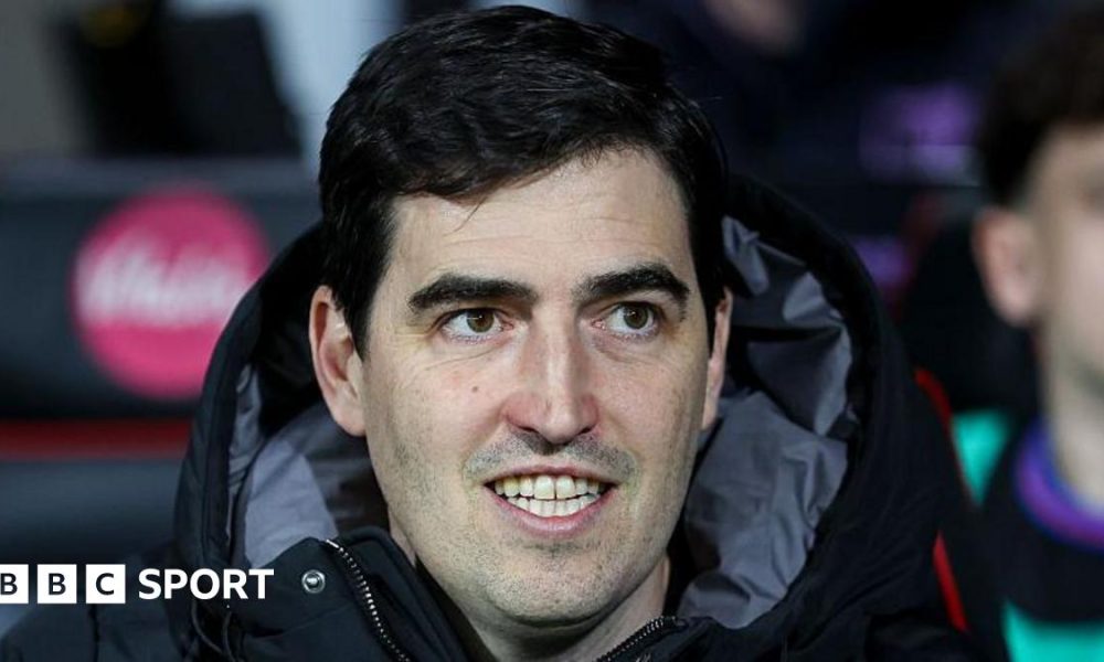 Bournemouth manager Andoni Iraola smiles as he watches a match