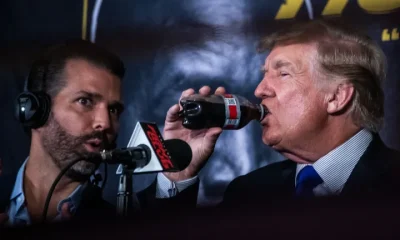 President Donald Trump drinks a soda as he hosts the Holyfield vs Belford boxing match live in 2021, next to his son Donald Trump Jr.