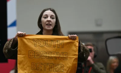 A demonstrator gets up and shows a banner reading "Youth Deserve Better" during the launching speech of Britain's main opposition Labour Party election manifesto booklet, in Manchester, on June 13, 2024