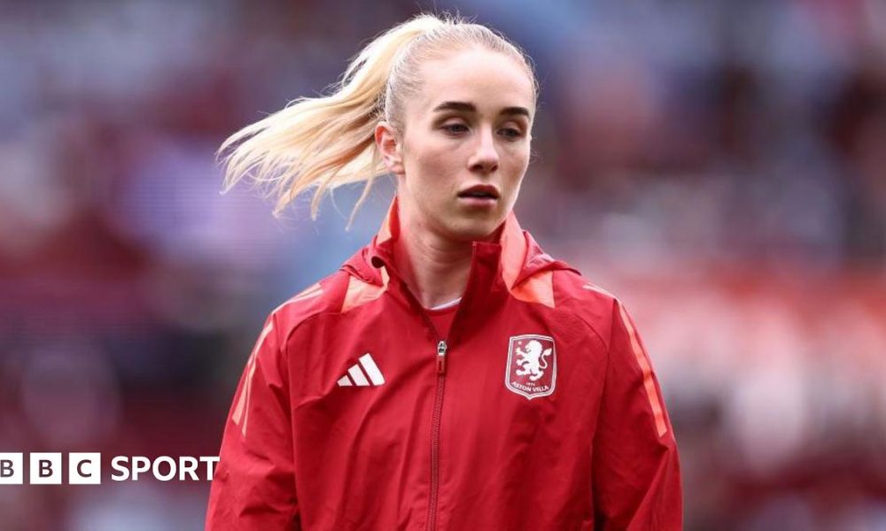 Missy Bo Kearns wearing a red jacket with an Aston Villa badge on the chest