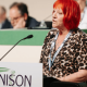 Andrea Egan speaking at the 2026 Unison health conference wearing her Unison lanyard and standing infront of a mic