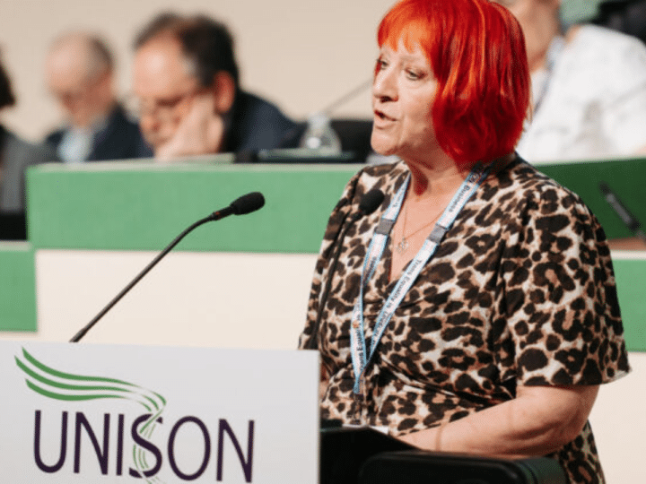 Andrea Egan speaking at the 2026 Unison health conference wearing her Unison lanyard and standing infront of a mic