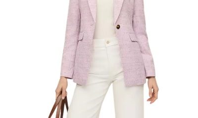 A woman wearing a pink tweed blazer with white pants and white top. She is carrying a tan tote.