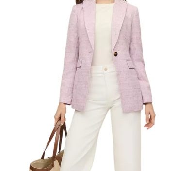 A woman wearing a pink tweed blazer with white pants and white top. She is carrying a tan tote.