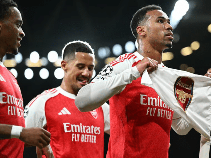 Arsenal players celebrate their 4-0 win over Atletico Madrid in October 2025. One players holds a t-shirt with the Arsenal emblem printed on it