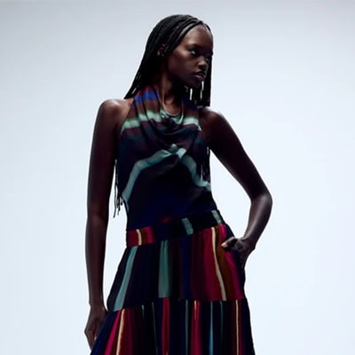 A woman wearing a multicolored striped top and coordinating balloon pants