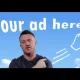 Tommy Robinson with a sign behind him which reads 'your ad here'