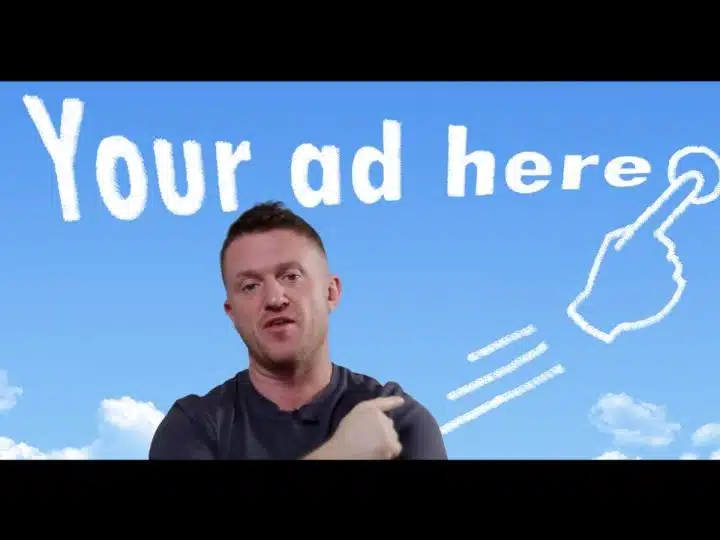 Tommy Robinson with a sign behind him which reads 'your ad here'
