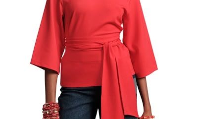 A woman wearing a red wrap top, dark blue jeans, and multiple red bracelets