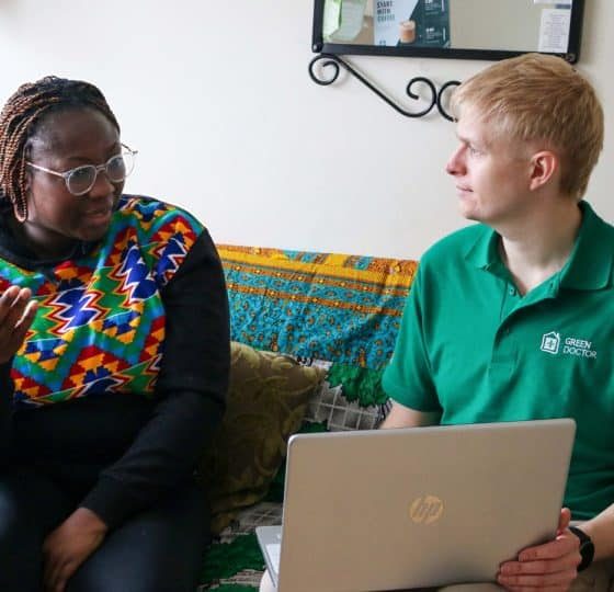 Green Doctors project manager, Daniel Brittle, holding a laptop, speaking to service user Pearl.