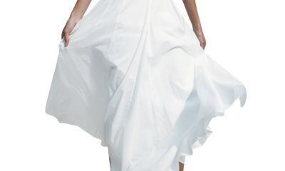 A woman (lower half of body shown) wearing a white top, white skirt, and white sandals