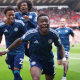 Abdul Fatawu celebrates with his Leicester teammates after scoring the winner against Charlton in August 2025. His mouth is open as he runs towards the photographer and his two teammates smile and laugh behind him