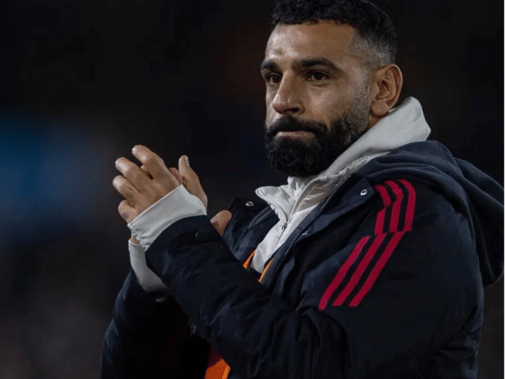 Liverpool player, Mo Salah, claps his hands together and looks somewhat morose looking on in the distance