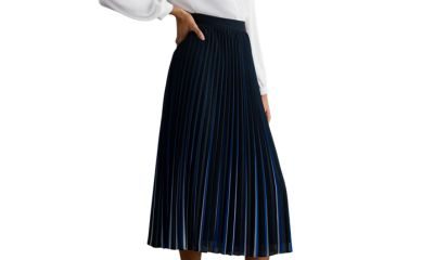 A woman wearing a white blouse and blue midi skirt with black slingbacks