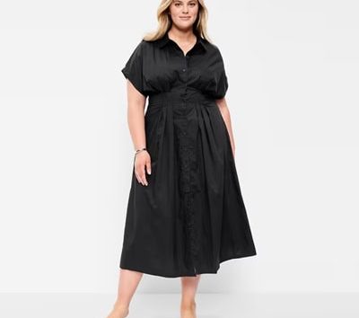 A woman wearing a black midi shirtdress and black sandals