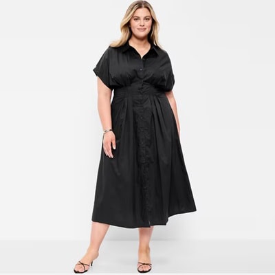 A woman wearing a black midi shirtdress and black sandals