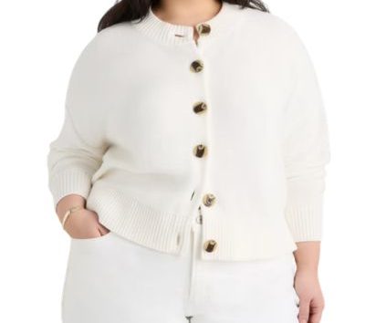 A woman wearing white pants and an ivory cardigan