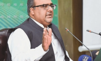 Shazad Akbar, a Pakistani dissident, speaks in front of small news microphones