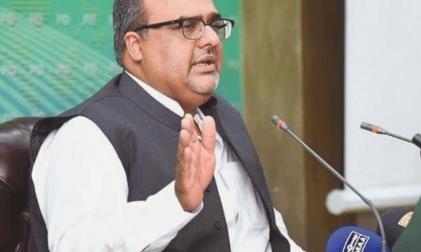 Shazad Akbar, a Pakistani dissident, speaks in front of small news microphones