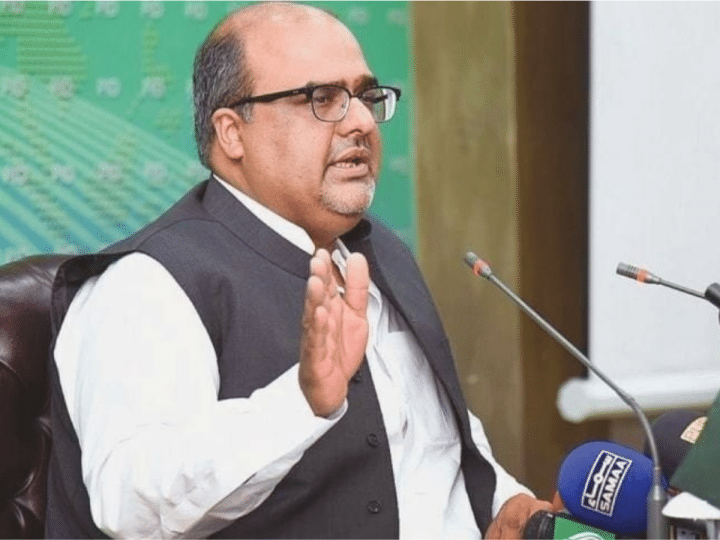 Shazad Akbar, a Pakistani dissident, speaks in front of small news microphones