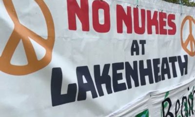 Banner with peace symbols attached to fence that reads: "No nukes at Lakenheath".