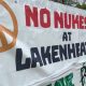 Banner with peace symbols attached to fence that reads: "No nukes at Lakenheath".