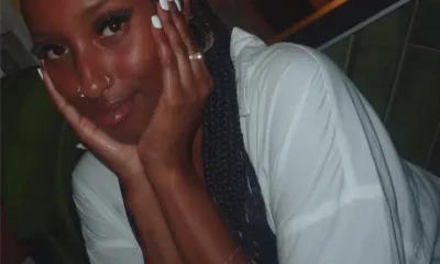 Zahwa Salah Mukhtar holds her face in her hands and smiles angelically with her mouth closed. Her finger nails are painted white and she's wearing a white blouse. You can just see her hearing aid in her left ear.