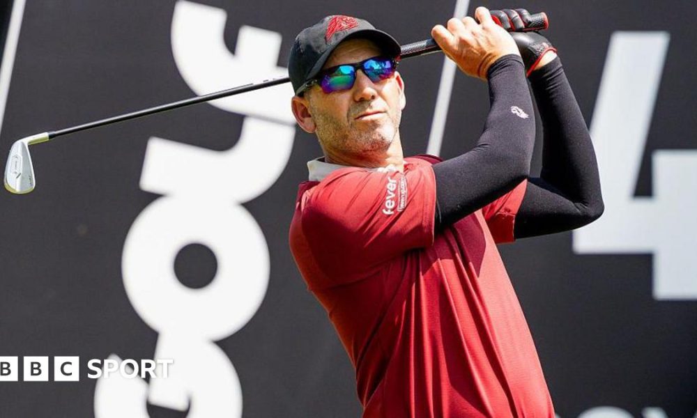Sergio Garica tees off during a LIV Golf tournament with the branding in the background