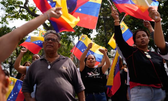 People gather at a government-organized event to watch former President Nicolas Maduro and first lady Cilia Flores appear in a New York court on a screen in Caracas, Venezuela, on March 26, 2026.