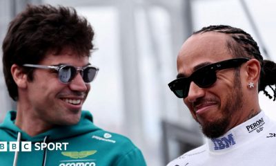 Aston Martin driver Lance Stroll and Ferrari driver Lewis Hamilton smiling while in conversation at the 2026 Australian Grand Prix. Both men are wearing sunglasses