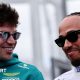 Aston Martin driver Lance Stroll and Ferrari driver Lewis Hamilton smiling while in conversation at the 2026 Australian Grand Prix. Both men are wearing sunglasses