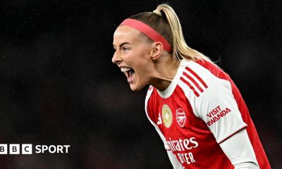 Chloe Kelly slides on her knees in celebration while wearing Arsenal's red and white kit and a red headband
