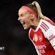 Chloe Kelly slides on her knees in celebration while wearing Arsenal's red and white kit and a red headband