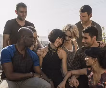 The cast of Sense 8 huddle around Bae Doona on a rooftop balcony. 